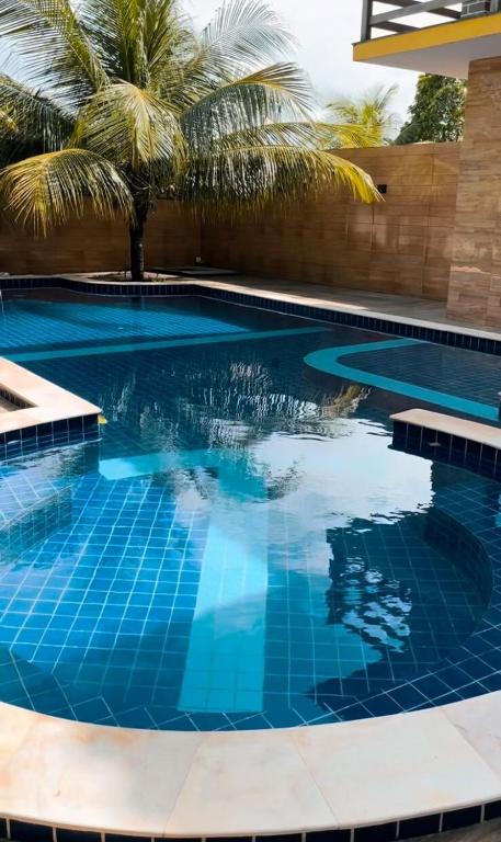 a swimming pool with blue water and palm trees at Paraiso da Lagoa in Estância