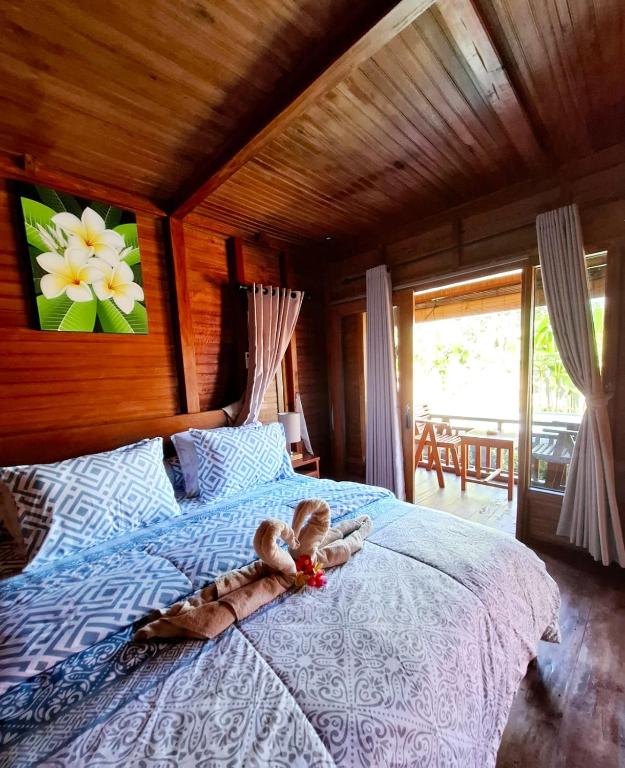 a bedroom with a bed with a teddy bear on it at Pondok Denly by Pigeon in Nusa Dua