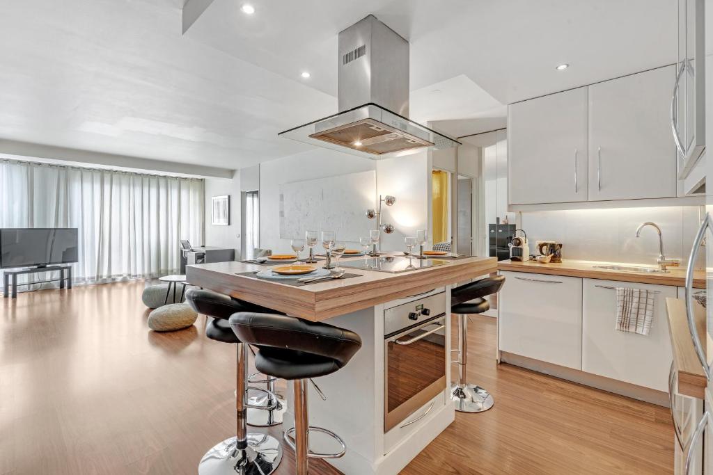 a kitchen with white cabinets and a kitchen island with bar stools at Appartement Saint Tropez in Saint-Tropez