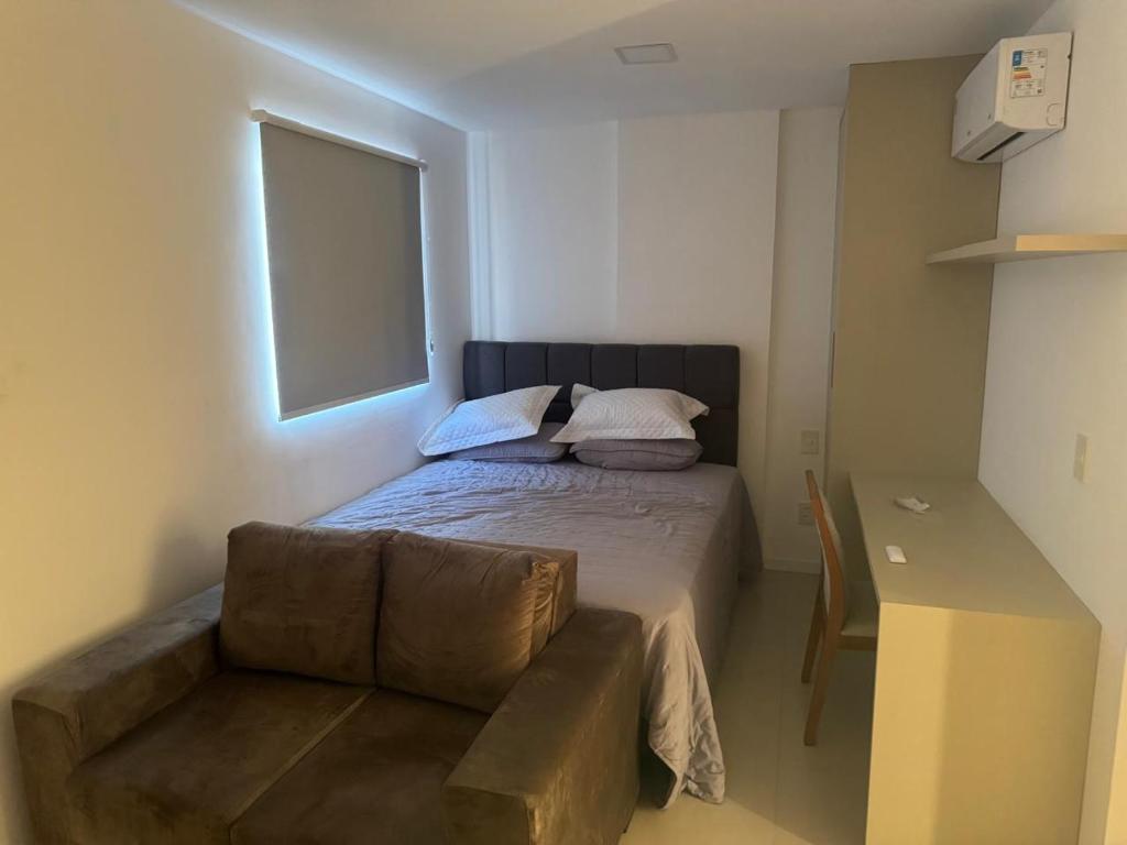 een kleine slaapkamer met een bed en een bank bij Studio V Ininga - 610 in Teresina
