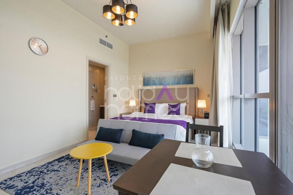 Un dormitorio con una cama, una mesa y un sofá. en Elegant Studio apartment in Avanti Tower Business Bay, en Dubái