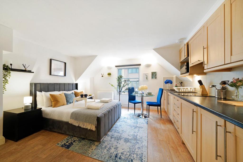 a bedroom with a bed and a kitchen with a table at Stylish Studios in Historic City of London, Next to Barbican & Farringdon in London