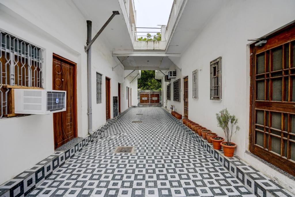 a corridor of a house with white walls and a black and white tile floor at SPOT ON Manjuvilla in Varanasi