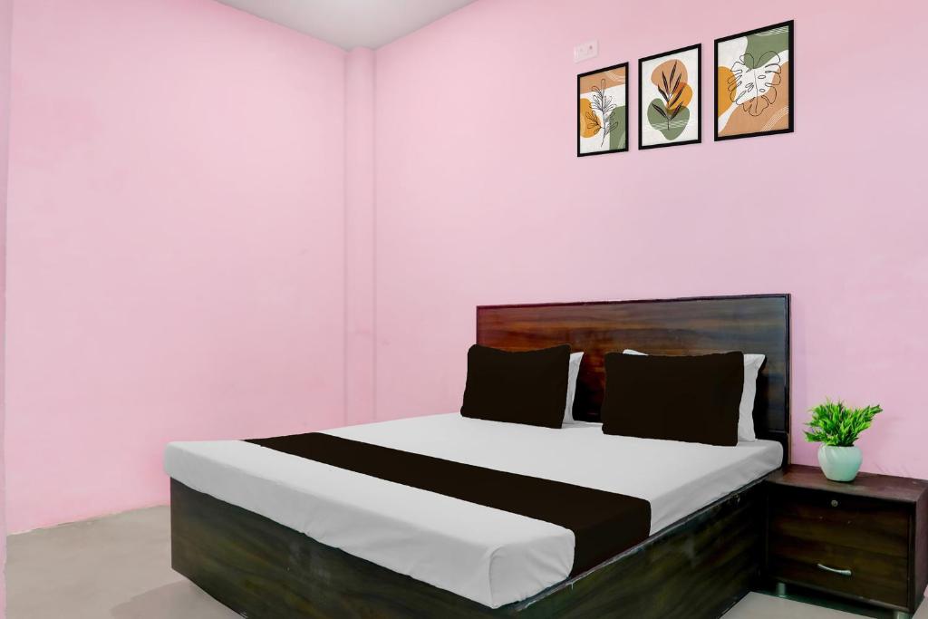 a bedroom with a large bed in a pink room at SPOT ON Mahal Guest House in Paikbara
