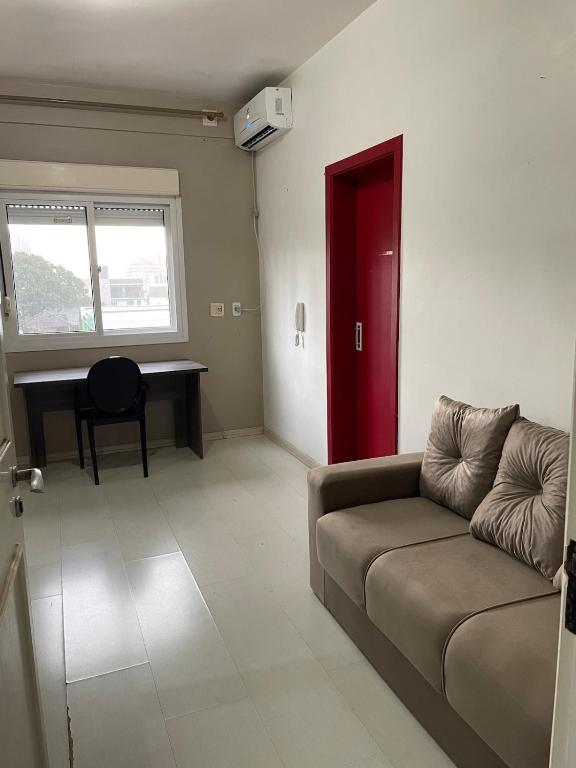- un salon avec un canapé et une porte rouge dans l'établissement JK prox Regina e Feevale com AC e espaço Home Office, à Novo Hamburgo