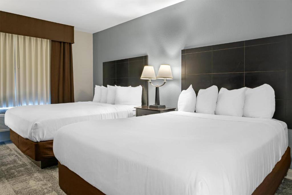 two beds in a hotel room with white beds at Best Western Lakewinds in Ludington