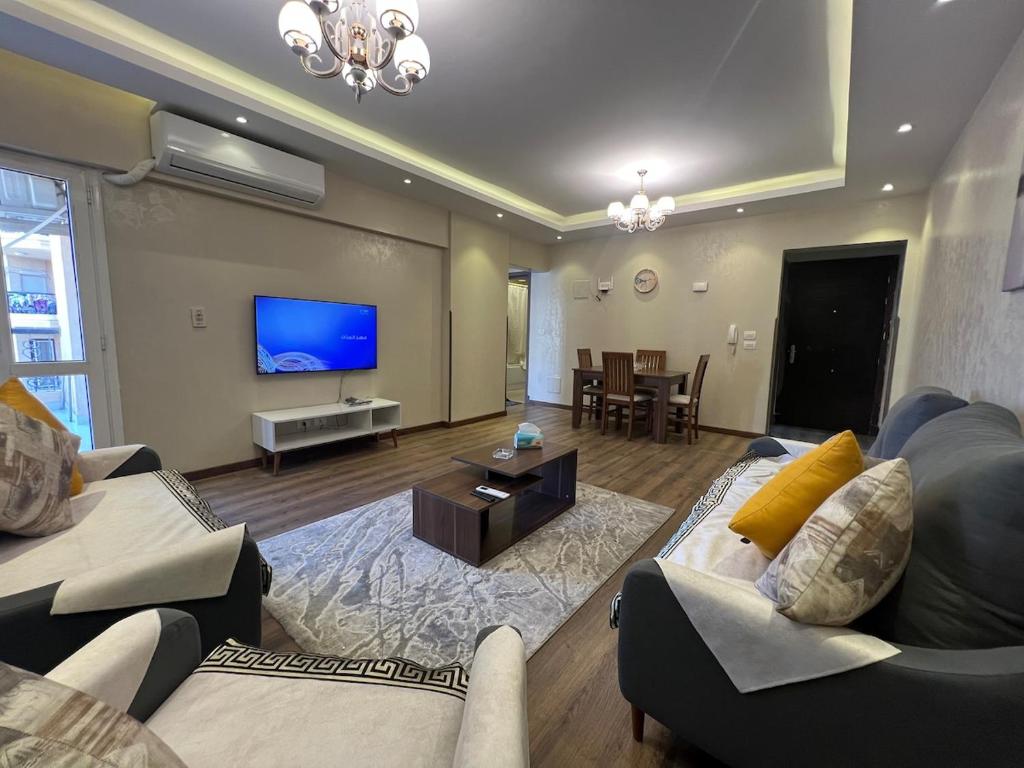 un salon avec des canapés et une télévision à écran plat dans l'établissement Cozy cheap apartment, à Burg el-Ḥudûd