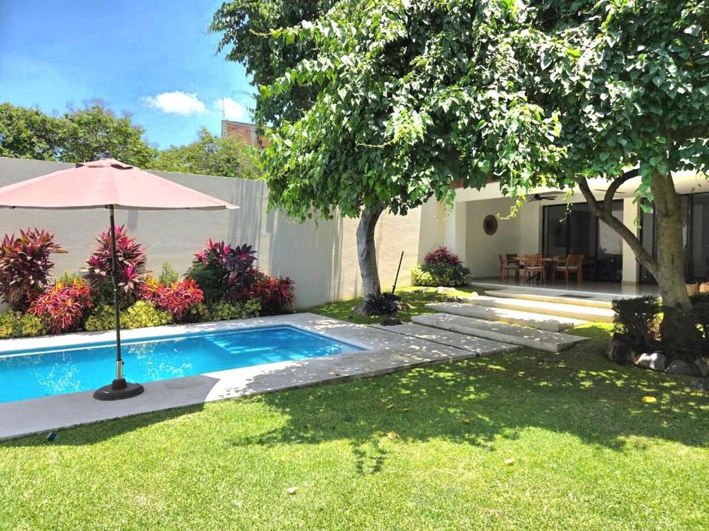 a swimming pool in a yard with an umbrella at Burgos Cuernavaca Pool Terrace & Garden in Temixco