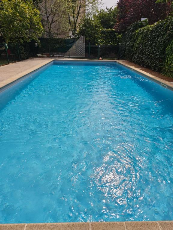 a large pool with blue water in a yard at Appartement de charme, Garage, Terrasse, Piscine in Lyon