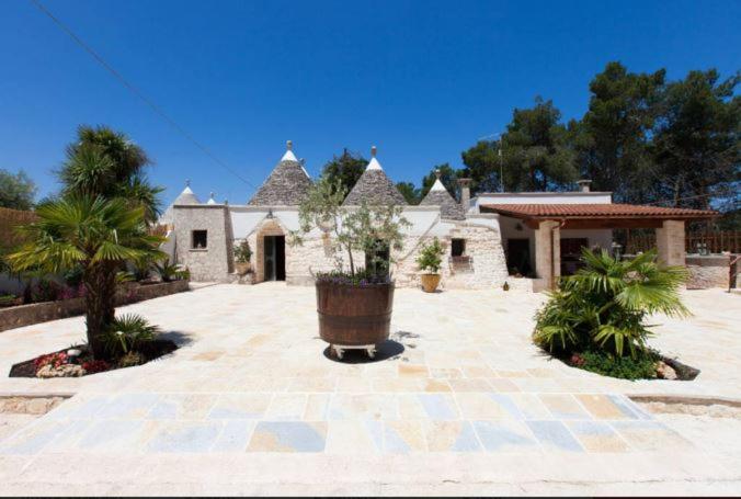 a house with a large courtyard with palm trees at Trullo Abbracciavento in Martina Franca
