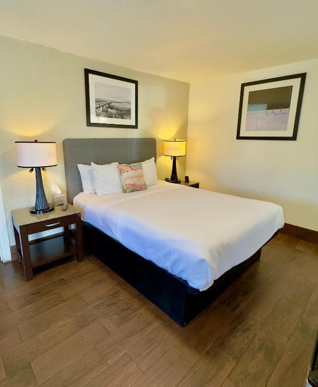 Un dormitorio con una gran cama blanca con dos lámparas. en Budget Motel, en Gilroy