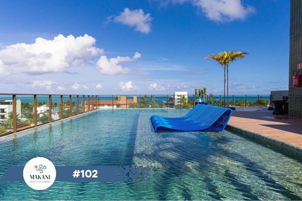 uma piscina com uma cadeira azul num edifício em Makani Beach Flat Campas #102 - Frente Norte Alto Padrão em Tamandaré