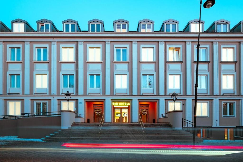 a building with red doors and stairs in front at B&B HOTEL Kalisz Centrum in Kalisz