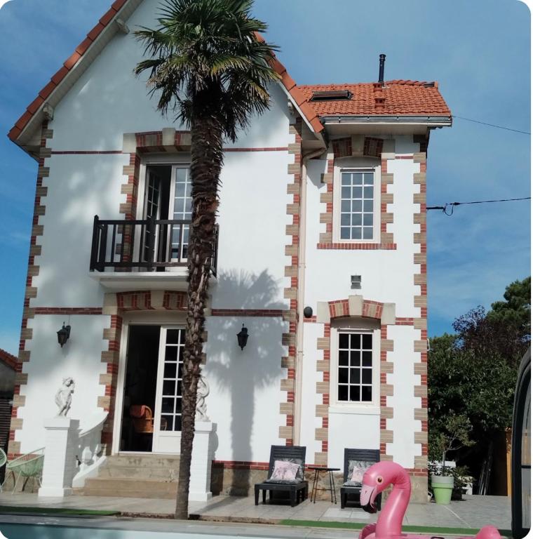 a house with a palm tree in front of it at VILLA 1900 Bord de mer piscine SPA Nordique in Saint-Brevin-les-Pins