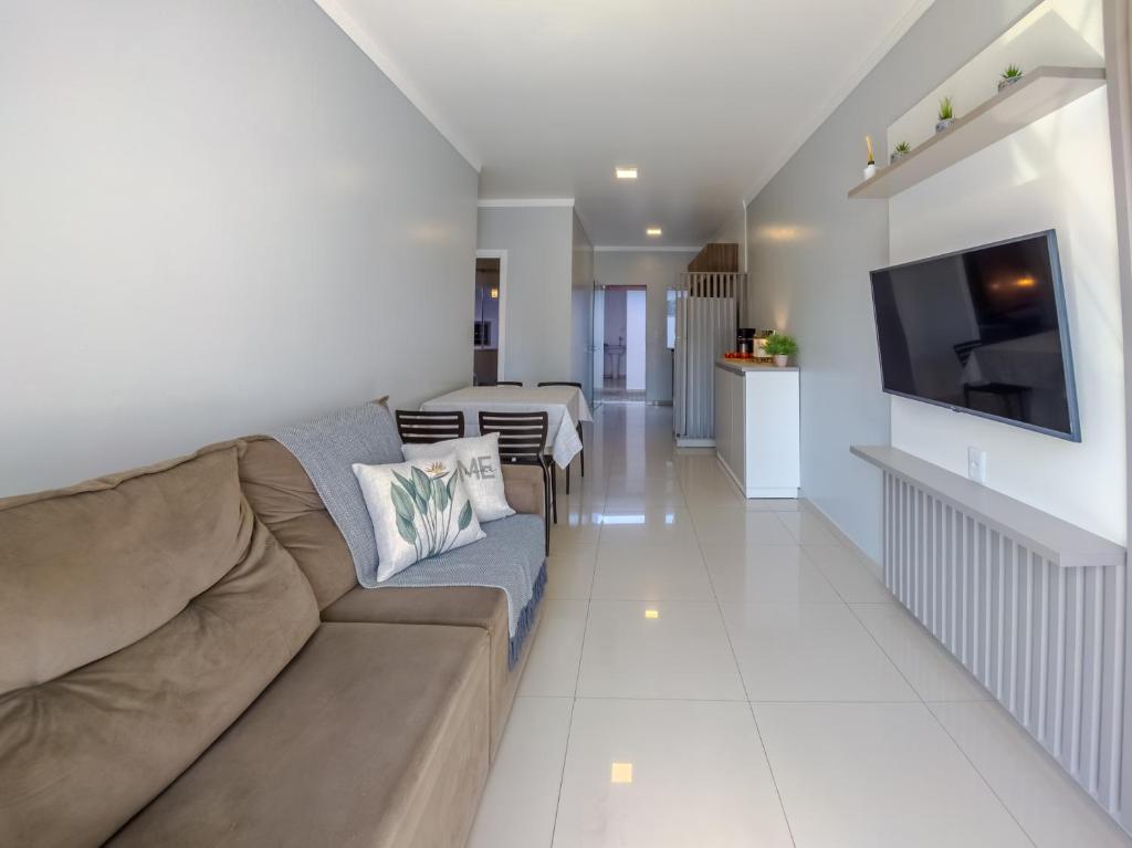 a living room with a couch and a television in it at Curta Praia da Armação - Casa Tulipa in Penha