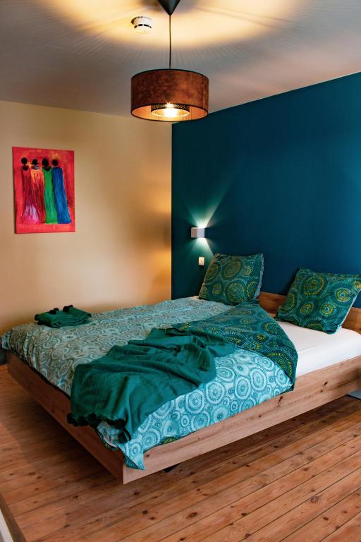 a bedroom with a bed with a blue wall at Au vent des Blés Chambre Marguerite in Incourt