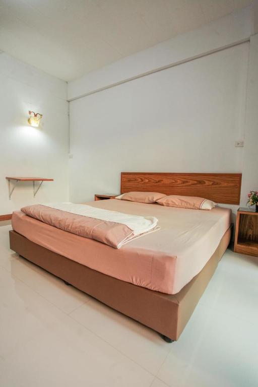 a bedroom with a large bed with pink pillows at โรงแรมบ้านสวน ฟ้าใส in Chanthaburi