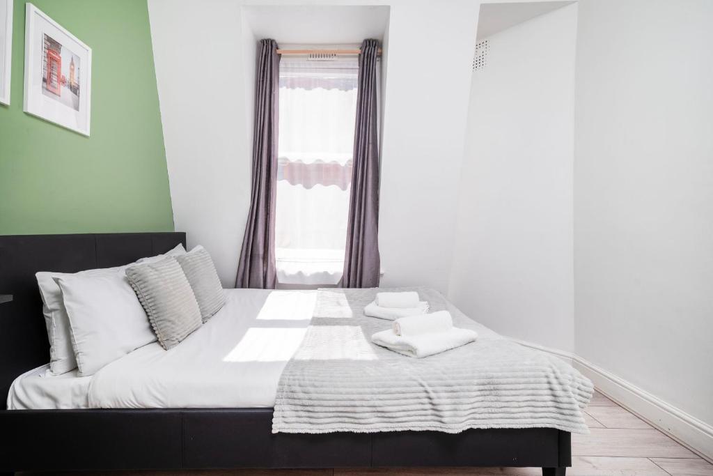 a bedroom with a bed with white sheets and a window at Strand Central Apartments 4th Floor in London
