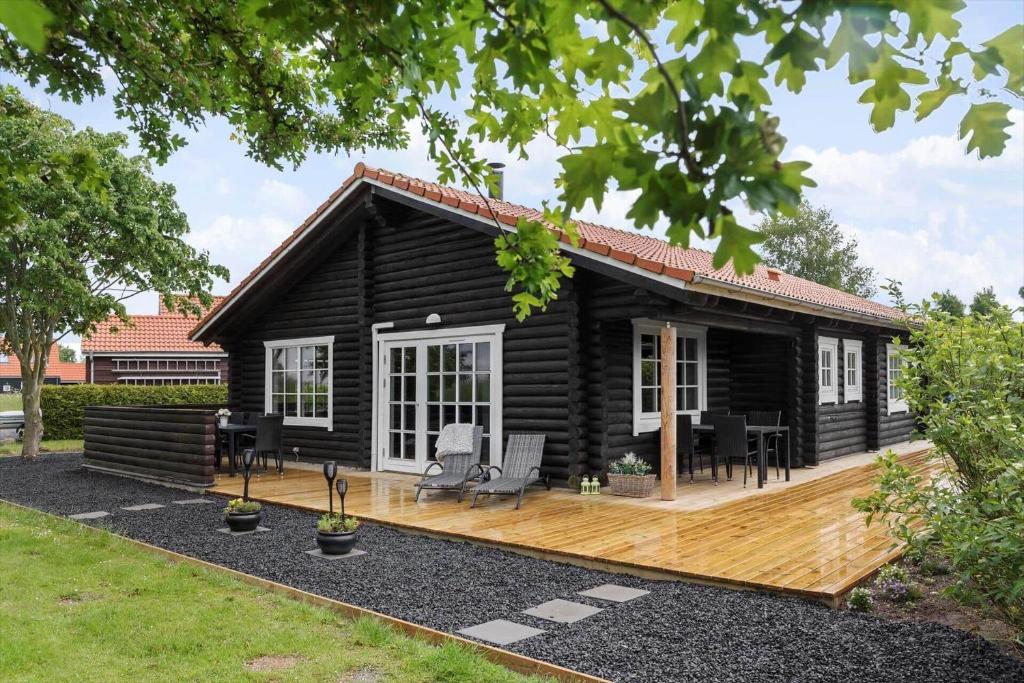 a log cabin with a wooden deck and chairs at M212-Vaeggerlose-Marielyst-Strandpark-127 in Marielyst