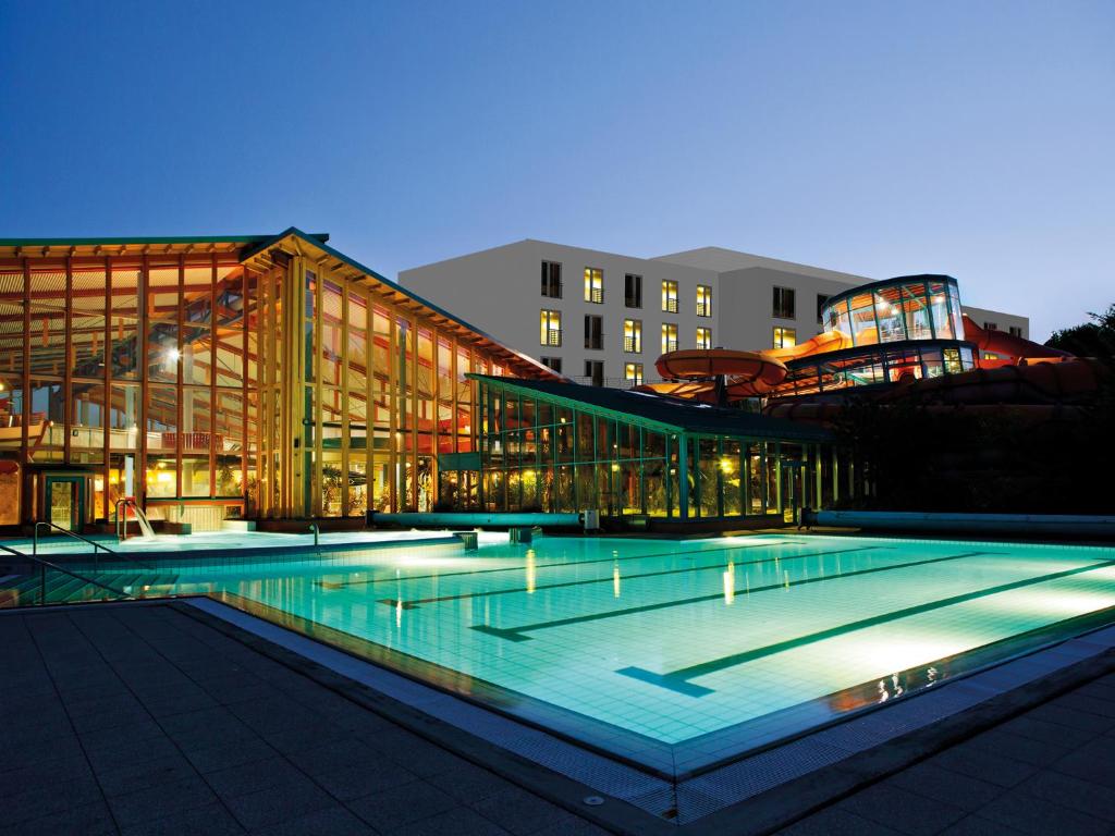 a large building with a swimming pool at night at WONNEMAR Resort-Hotel in Wismar