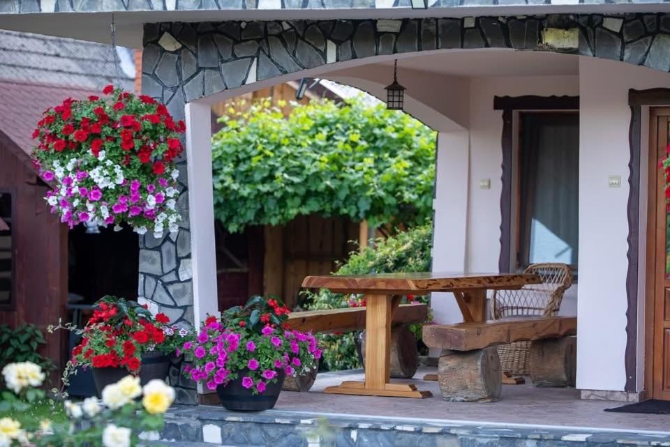 a patio with a wooden bench and flowers at Pensiunea Alina in Vama Buzăului