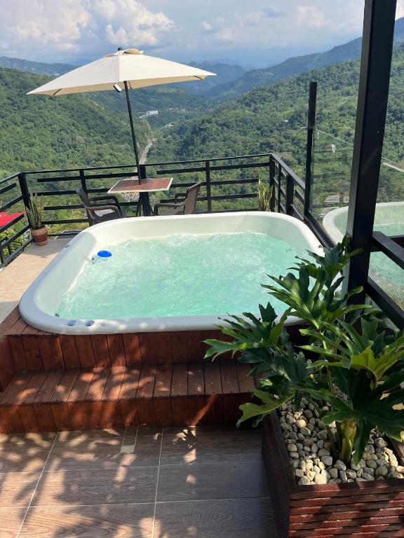 a hot tub on a deck with an umbrella at Romantic Glamping - Vista Impresionante Villeta Jacuzzi in Villeta