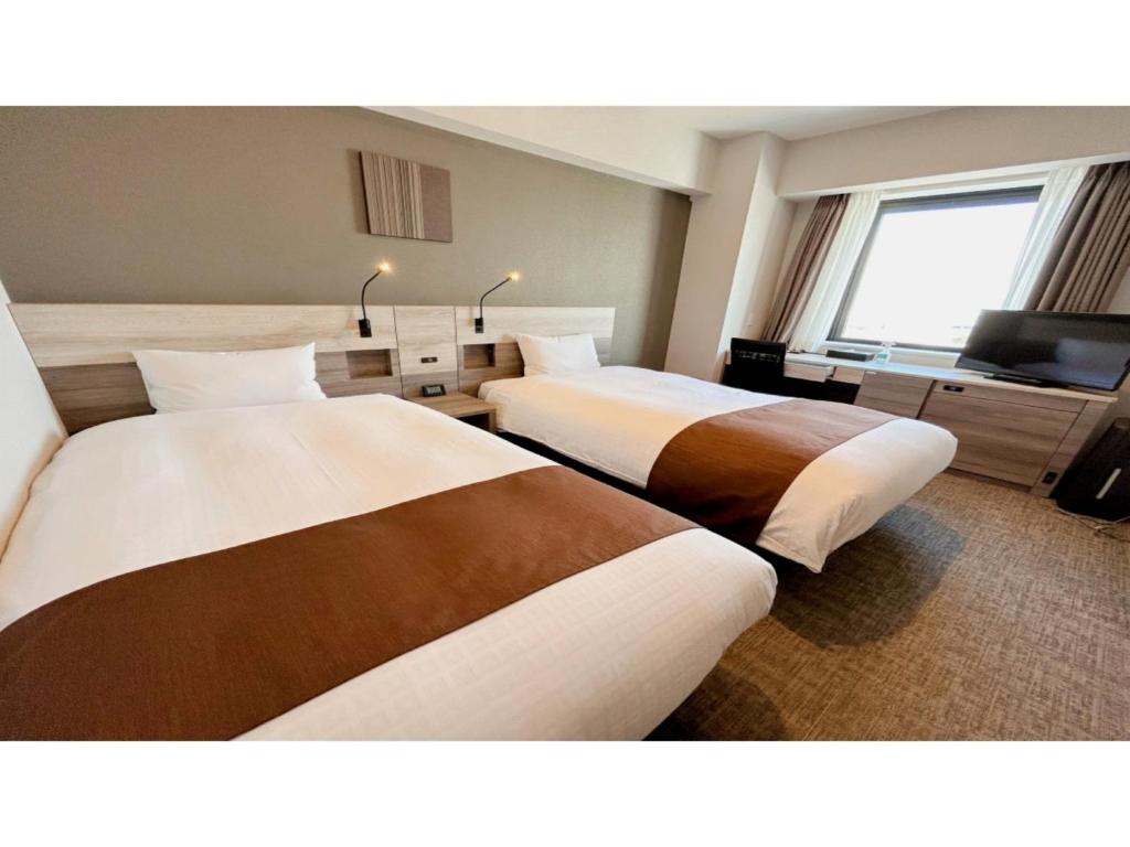 a hotel room with two beds and a television at Smile Hotel Premium Hakodate Goryokaku - Vacation STAY 97566v in Hakodate