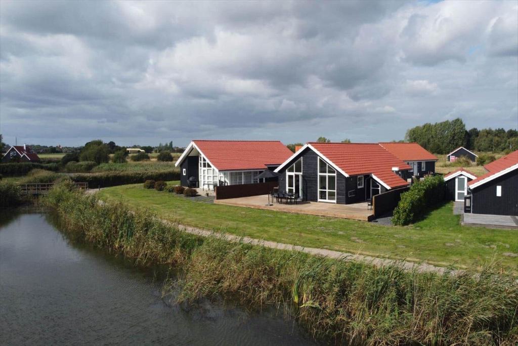 une maison aux toits rouges au bord d'une rivière dans l'établissement M226-Vaeggerlose-Marielyst-Strandpark-253, à Bøtø By