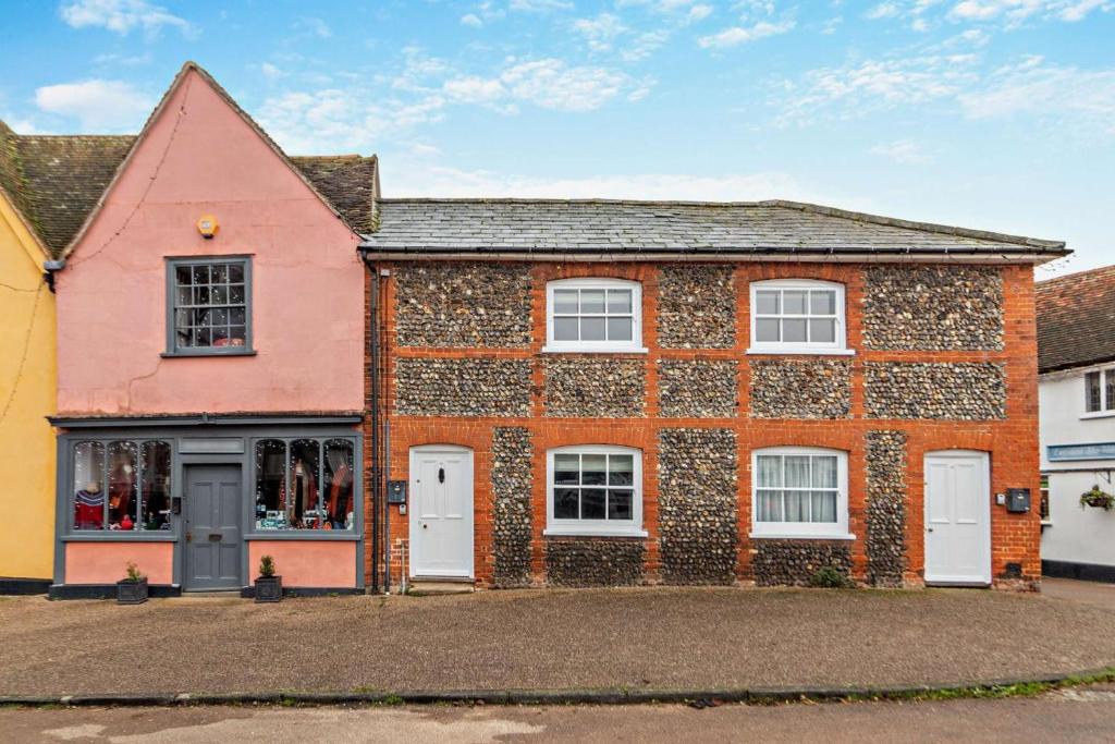 a red brick house with white doors and windows at Hawker Cottage in Lavenham