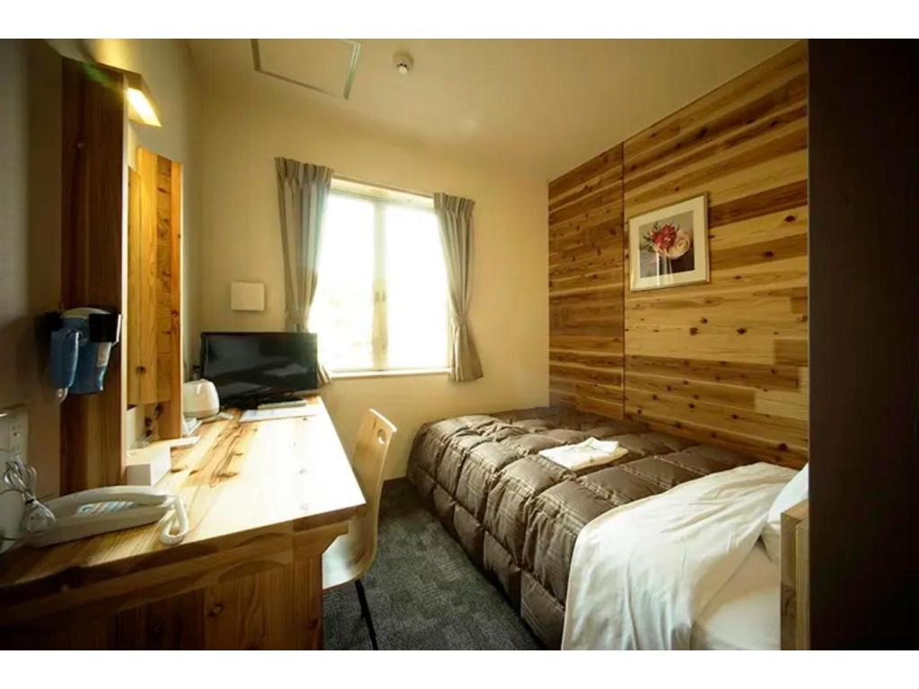 Un dormitorio con una cama y un escritorio con una computadora. en Maniwa City Hotel Sunrise - Vacation STAY 98583v, en Maniwa