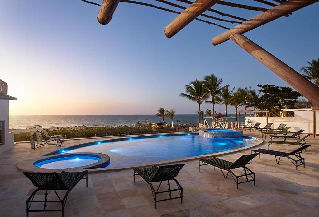 a pool with chairs and the ocean in the background at Pousada Villa Tibá in Jericoacoara