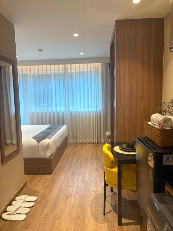 バンコクにあるApartment in Central Sukhumvitのベッド、デスク、黄色い椅子が備わるホテルルームです。