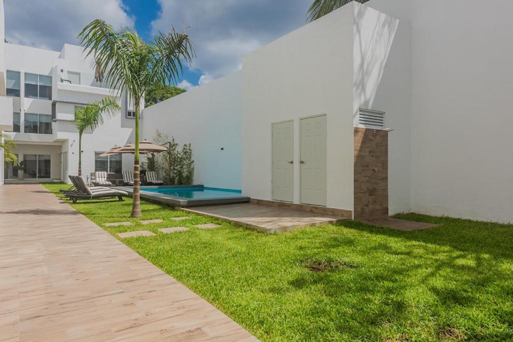 un cortile di un edificio bianco con una palma di Malibu Residential 3BD - Manduli a Cozumel