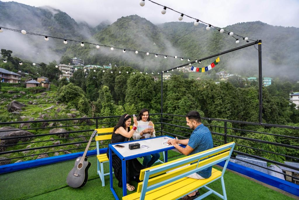 Un grupo de personas sentadas en una mesa en un balcón. en Shalom Backpackers Dharamkot McLeodganj, en McLeod Ganj