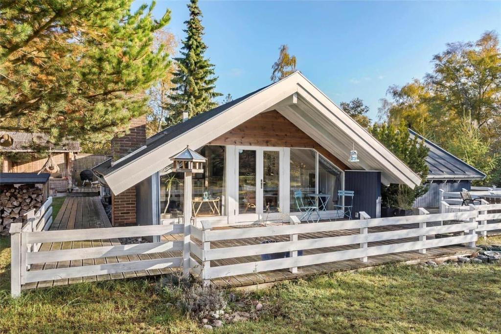 a small house with a white fence in the grass at L18-Rodby-Vibevej-9 in Rødby