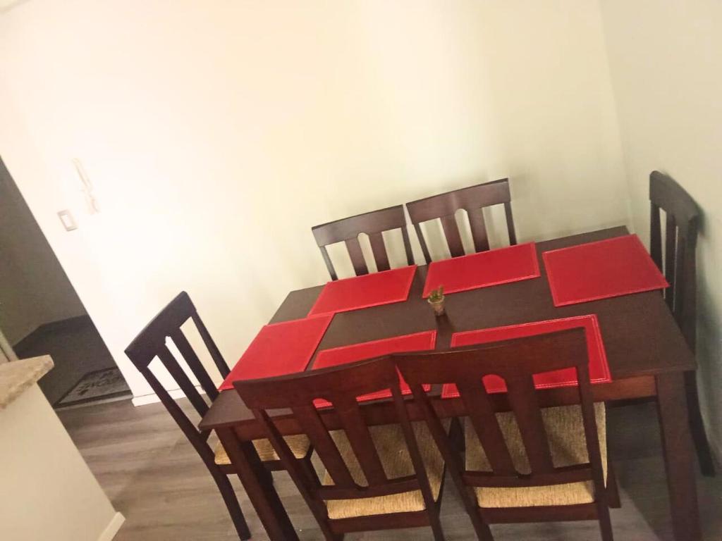 une table de salle à manger en bois avec des chaises rembourrées rouges dans l'établissement Departamento La serena, à La Serena