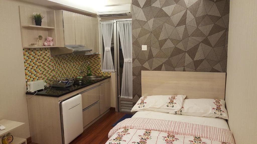 Un pequeño dormitorio con una cama y una cocina. en Papilukas Room Kalibata City - Studio Silver, en Yakarta