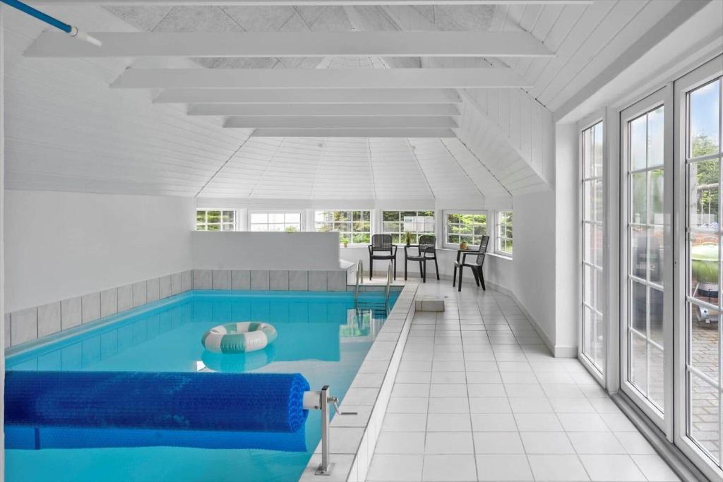 a swimming pool with blue water in a room with windows at M386-Vaeggerlose-Skarntydevej-27 in Bøtø By