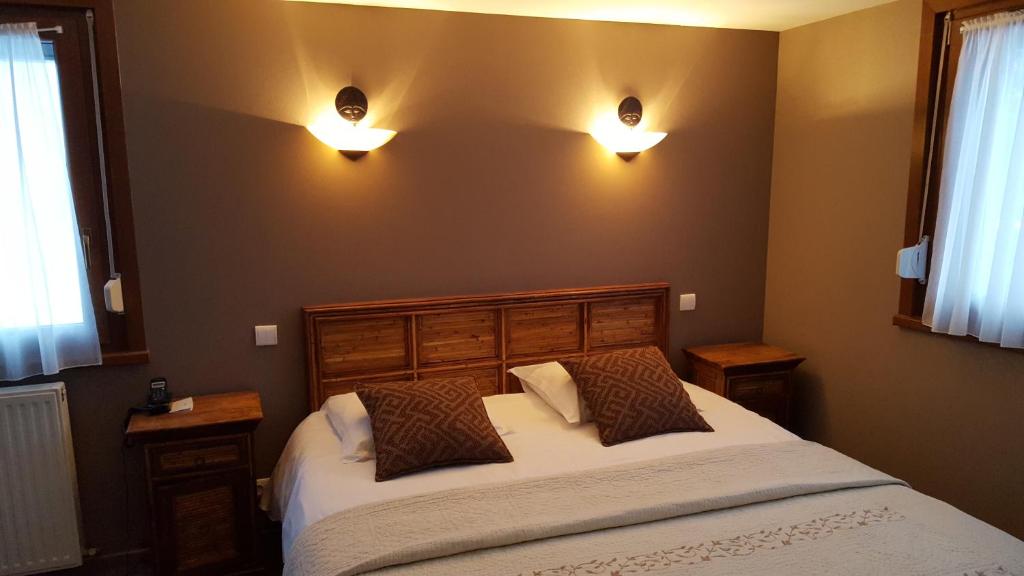 a bedroom with a bed and two lights on the wall at Hotel Les Sapins in Le Ménil