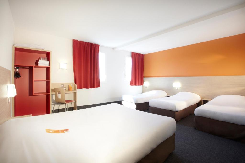 a hotel room with two beds and red curtains at Première Classe Istres in Istres