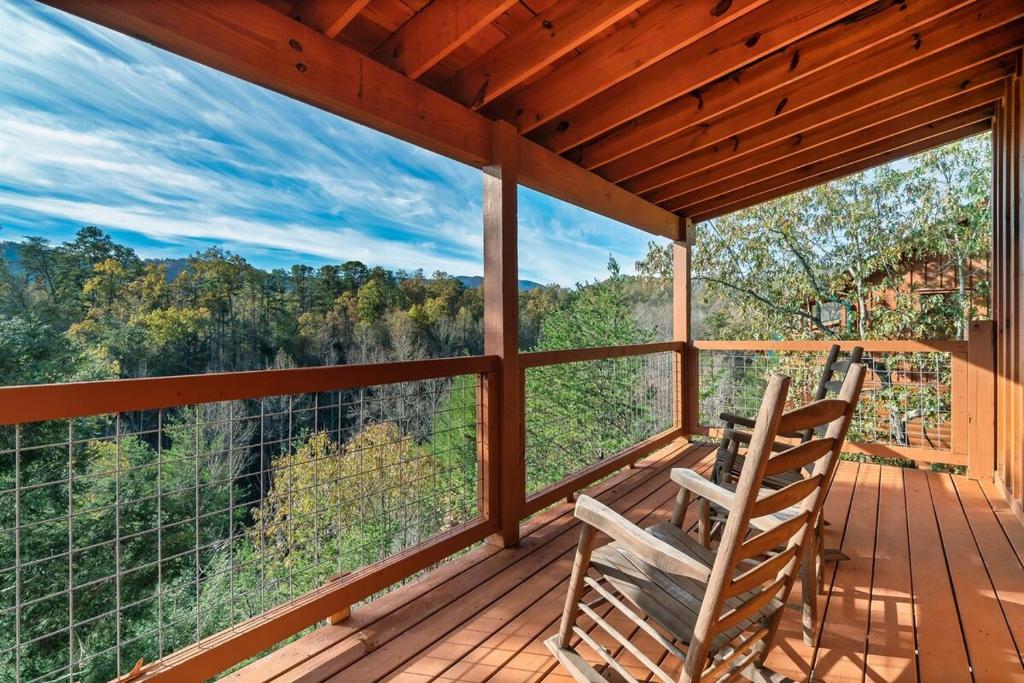 two chairs sitting on a porch with a view of the forest at Discounted! Heated Pool, Theater, Game Room, Pets in Pigeon Forge