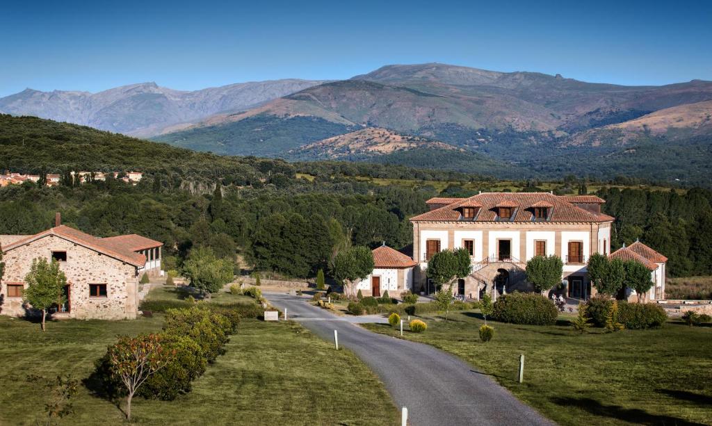 uma casa numa estrada com montanhas ao fundo em Izan Puerta de Gredos em El Barco de Ávila