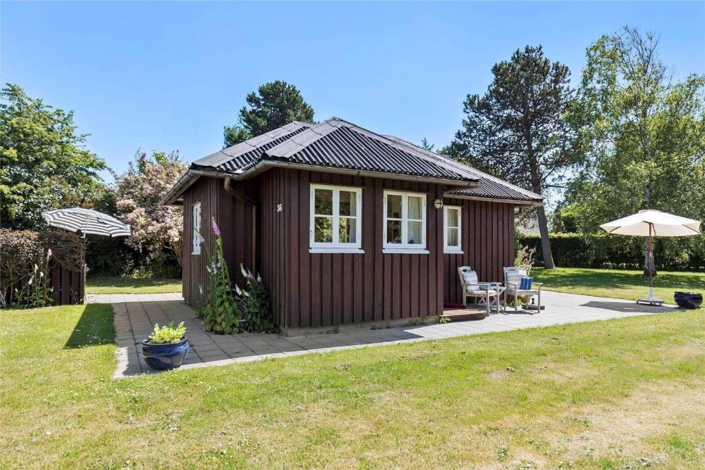 a small cabin with a patio and an umbrella at SL078-Slagelse-Dybkaervej-36 in Slagelse