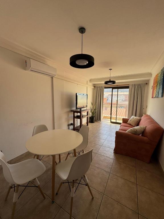 Una sala de estar con una mesa y sillas y un sofá. en Departamento Caseros, en Salta