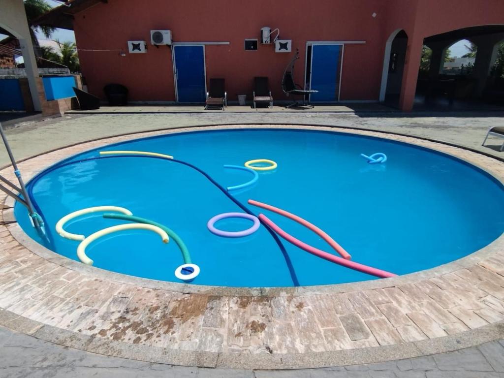 a blue swimming pool in front of a red building at Casa com Piscina Grande em Salinas in Salinópolis