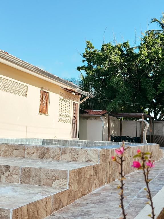 ein Haus mit einer steinernen Mauer und einem Zaun in der Unterkunft CasAMAR - casa de praia na terra das piscinas naturais - PE in São José da Coroa Grande