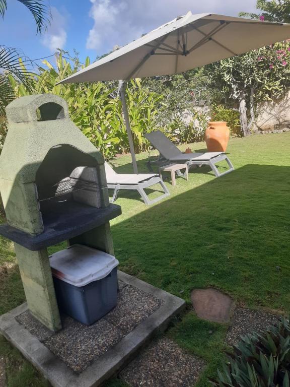 a stone stove in a yard with an umbrella at Le Jardin aux Oiseaux in Sainte-Anne