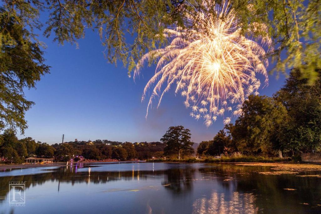 een vuurwerkshow boven een vijver in een park bij Shared Heated Pool Balcony BBQ Near Downtown in New Braunfels