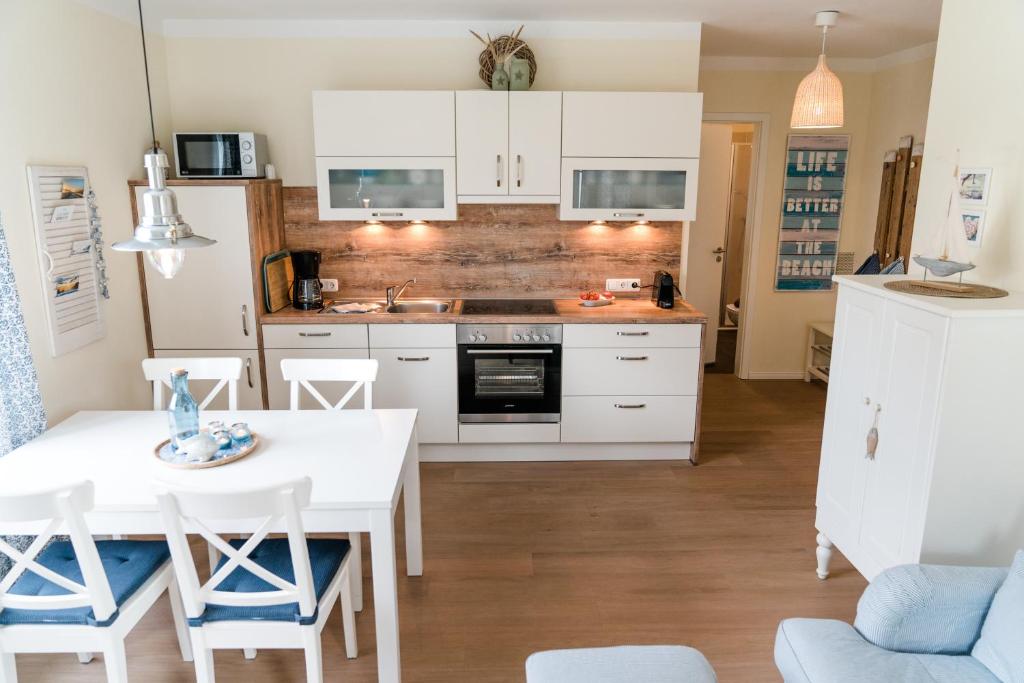 a kitchen with white cabinets and a table and chairs at Zimt & Zucker in Langeoog