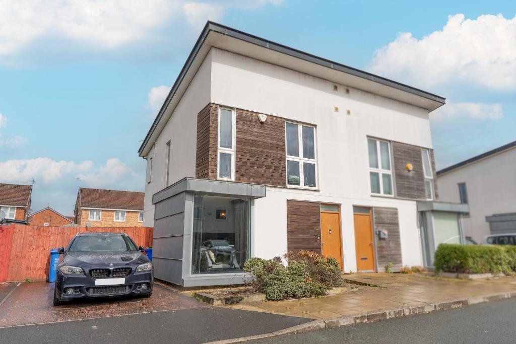 a white house with a car parked in front of it at Etihad Stadium Stay for Contractors with Free Parking & Wifi Near The City Stays in Manchester